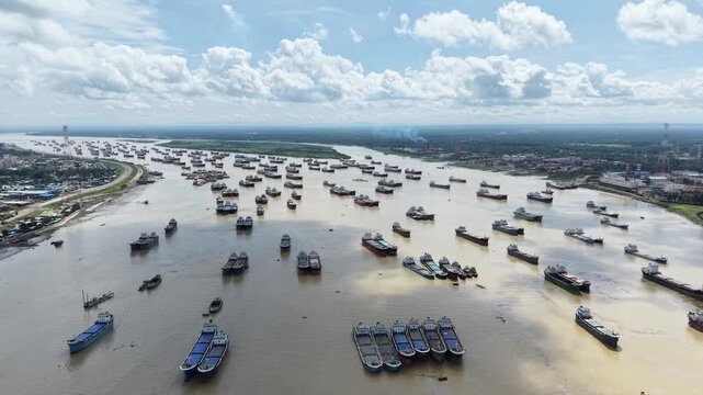 A broad drone view captures thousands of tons of cargo capacity sitting idle as lighter ships group together for safety on the Karnaphuli River in Chattogram, Bangladesh. 