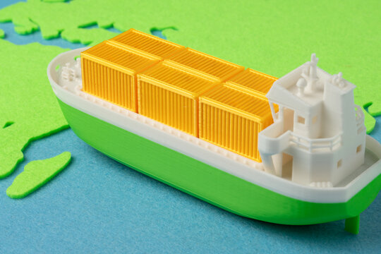 Green cargo ship sailing towards a green world map on a blue background. Eco-friendly shipping, carbon footprint reduction, maritime decarbonization, green supply chains concept.
