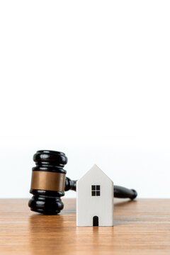 Miniature white house and judge gavel. Real estate law, property foreclosure, eviction, mortgage disputes, divorce asset division, housing regulations, and property auctions concept.