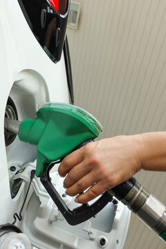 A person is filling a white vehicle with fuel at a station