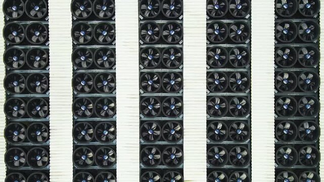 Industrial ventilation wall with rows of spinning cooling fans for server farm operation.