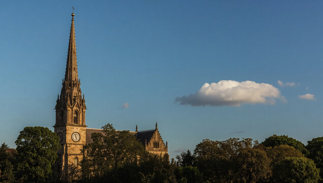 historic church tower with intricate stone carvings slate roof and tall spire against clear blue sky serene landscape warm sunlight peaceful atmosphere