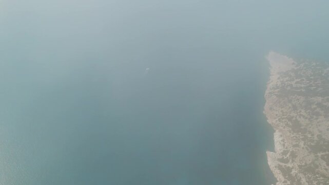 Aerial view of foggy coastline with faint outline of boat in Cephalonia Greece
