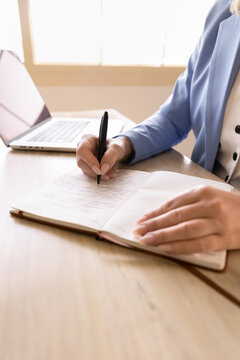 Closeup of professional woman make notes, writing information in notebook, documenting ideas, planning tasks sitting at office desk with laptop. Efficient task management, studying process, education