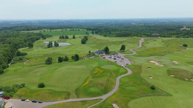 Devil's Paintbrush Golf Course clubhouse and parking lot sit amid rolling fairways and greens in this daytime drone pass.