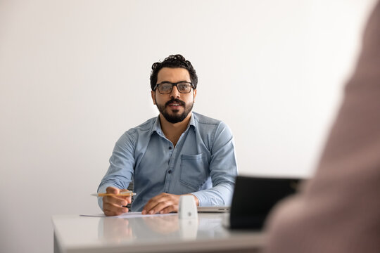 Middle eastern businessman engaging in conversation, professional communication during negotiations or job interview, sits at table talk to applicant or client. Corporate meeting, business discussion