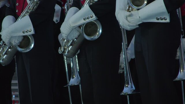Pan across marching band in uniform holding silver brass instruments