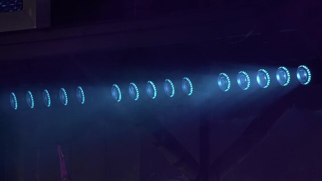 Blue stage lights glow dim, fog drifts on outdoor concert stage, detail