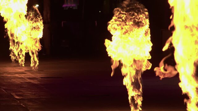flames burst from gas jets during outdoor stage show at night, detail