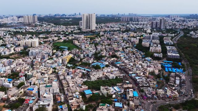 Aerial view of Chanda Nagar with Nallagandla road, vehicles, high-rise building and HYDERABAD CENTRAL UNIVERSITY forest at Lingampally, hyderabad, telangana, india. day time, arc shot, drone shot, 4k.