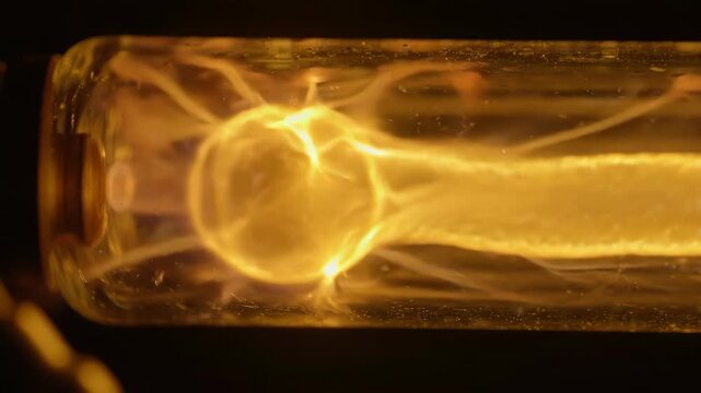 Glowing yellow neon tube light with warm illumination and detailed glass texture emitting bright glowing light closeup macro shot filament detail