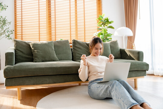 Funny euphoric young asian woman celebrating winning or getting ecommerce shopping offer on computer laptop. Excited happy girl winner looking at notebook celebrating success
