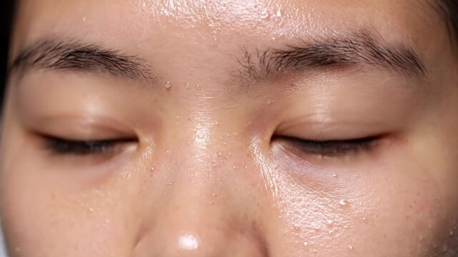 Woman applying makeup sponge to closed eyes. Female beauty routine with cosmetic blending tool for flawless skin.