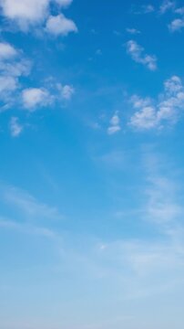 Peaceful daytime sky time-lapse with soft white clouds flowing in a deep blue atmosphere.