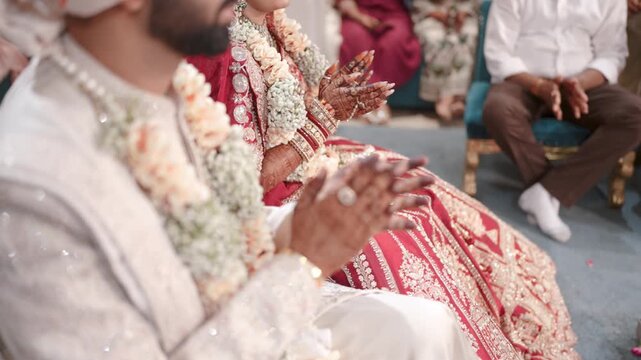 Close up of an Indian bride and groom clapping hands in joy during a traditional wedding ritual
