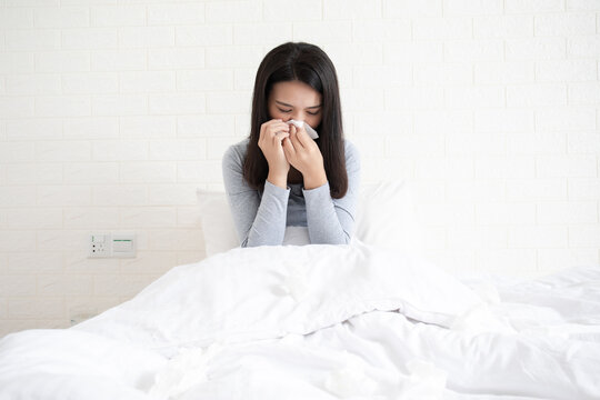A young Chinese woman with a cold on her bed