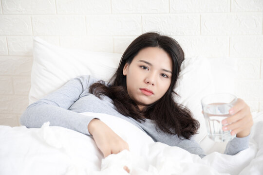 A young Chinese woman with a cold on her bed