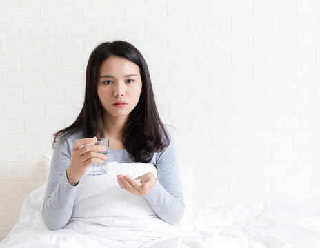 A young Chinese woman with a cold on her bed