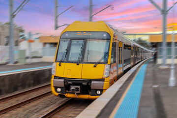 Fototapeta premium Passenger Train going through Lewisham Train Station at Sunset a suburban Sydney train Station in Sydney NSW Australia