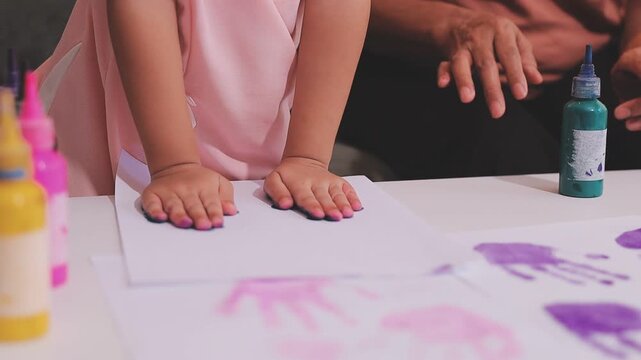 Small children hands hold wax crayons to draw rainbow on paper sheet. Diverse kids engage in creative craft activity together sitting on floor. Little students practice coloring skills at home school