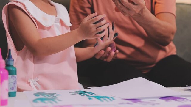 Small children hands hold wax crayons to draw rainbow on paper sheet. Diverse kids engage in creative craft activity together sitting on floor. Little students practice coloring skills at home school