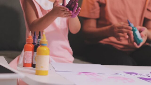 Small children hands hold wax crayons to draw rainbow on paper sheet. Diverse kids engage in creative craft activity together sitting on floor. Little students practice coloring skills at home school