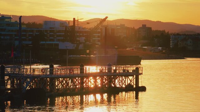 Symmetrical floating pedestrian dock at sunset in urban harbor