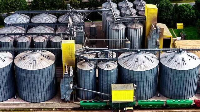 Aerial view of large industrial grain elevator complex with railway train freight cars moving cargo.