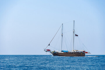 Fototapeta premium Traditional two masted sailing gulet floats on a calm blue sea under a clear sky, coastal boat charter.