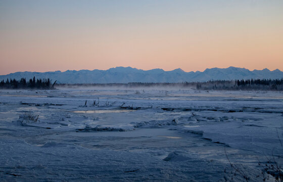 Wind blowing snow across frozen river
