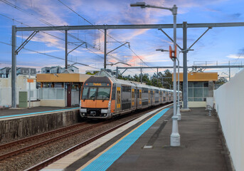 Fototapeta premium Passenger Train going through Lewisham Train Station at Sunset a suburban Sydney train Station in Sydney NSW Australia