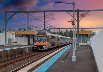 Fototapeta premium Passenger Train going through Lewisham Train Station at Sunset a suburban Sydney train Station in Sydney NSW Australia