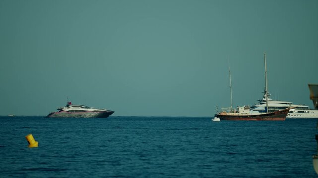 Different types of luxury yachts and sailing boats anchored on the deep blue sea, enjoying summer leisure and travel