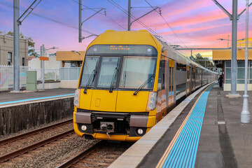 Fototapeta premium Passenger Train going through Lewisham Train Station at Sunset a suburban Sydney train Station in Sydney NSW Australia