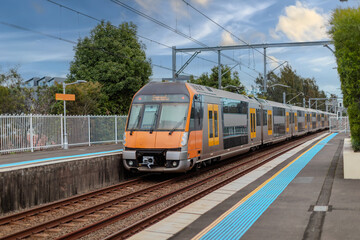 Fototapeta premium Passenger Train going through Lewisham Train Station at Sunset a suburban Sydney train Station in Sydney NSW Australia