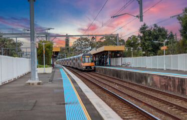 Fototapeta premium Passenger Train going through Lewisham Train Station at Sunset a suburban Sydney train Station in Sydney NSW Australia