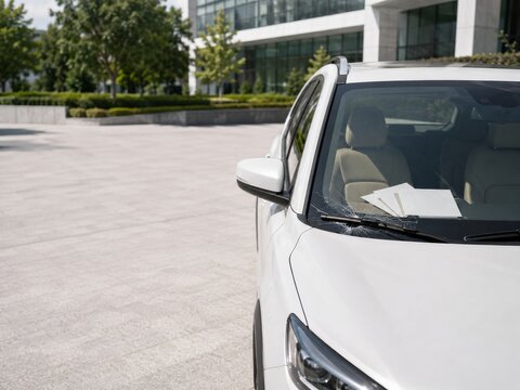 Se observa un coche blanco aparcado en un edificio moderno durante el d&iacute;a
