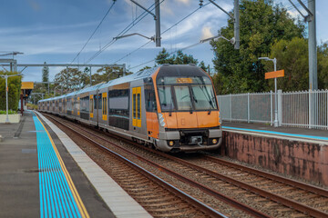 Fototapeta premium Passenger Train going through Lewisham Train Station at Sunset a suburban Sydney train Station in Sydney NSW Australia