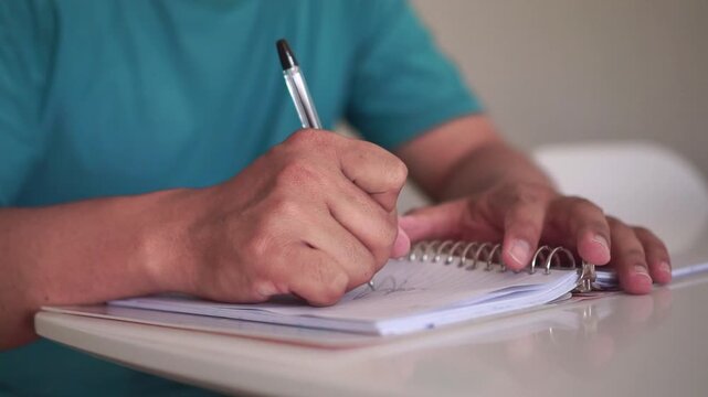 Frustrated person writing notes, crossing out handwritten text with pen. Concept of mistake, stress, deadline pressure, and failure at work or study.