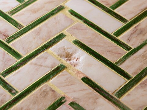 Herringbone stone tile floor with pink and green accents forms a geometric background for interior design, home renovation and high-end architectural advertising