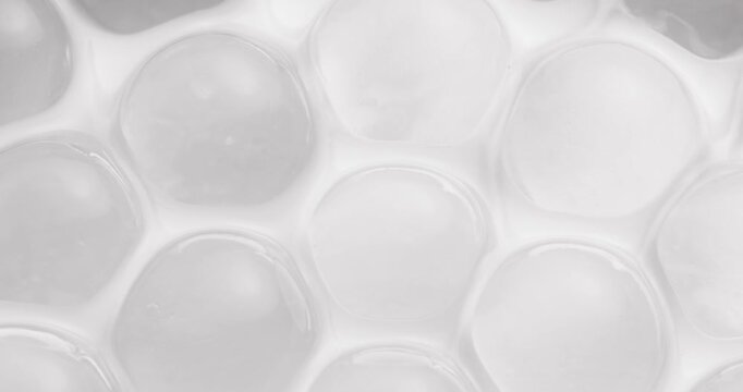 Panning shot of bubble wrap plastic sheet shifting across tabletop close up, concept experimental with microscope for cell structure.