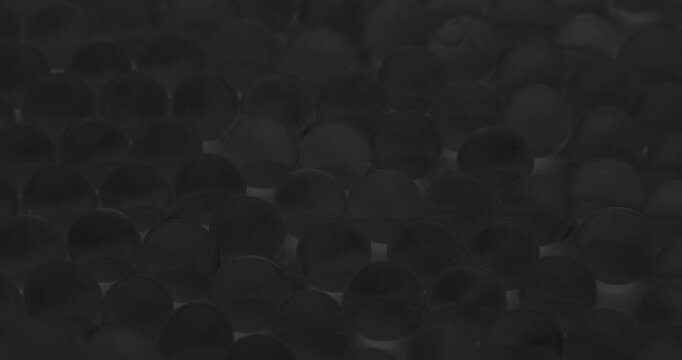 Slow motion glass beads rolling across tabletop studio closeup in monochrome, concept health experimental.