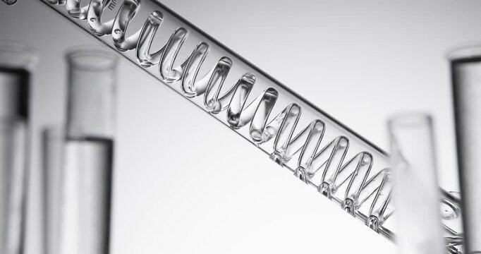 Slow motion spiral glass condenser moving over laboratory test tubes with shallow depth of field.