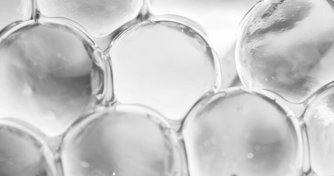 Slow motion close up of clear water beads shifting and compressing, concept experimental with microscope for cell structure.