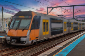 Fototapeta premium Passenger Train going through Lewisham Train Station at Sunset a suburban Sydney train Station in Sydney NSW Australia