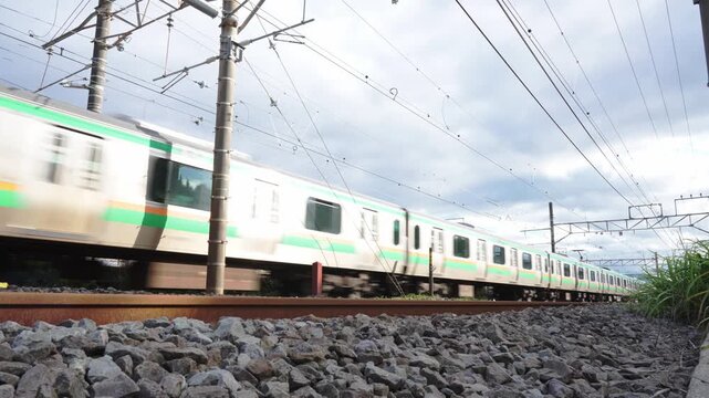 Dramatic low angle shot of a Japanese commuter train rushing past on a railway track