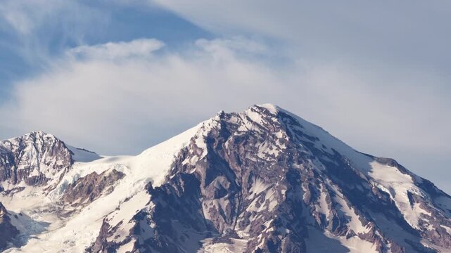 Aerial zoom shot of Mount Rainier summit with glacier fields with misty blue sky in Washington in summer