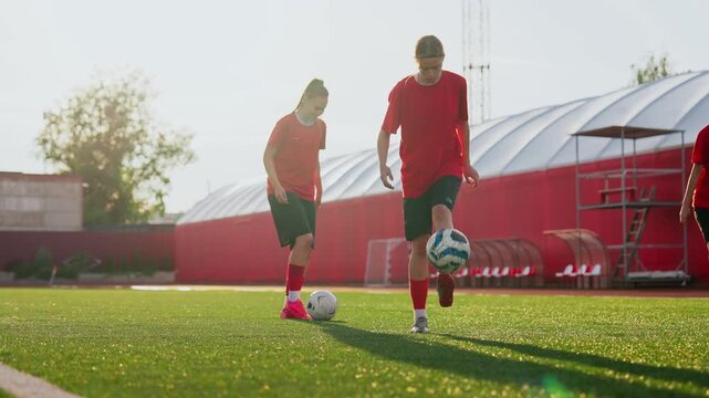 Focused womens soccer training session on artificial turf field with red uniforms, practicing ball control, dribbling, and coordination during outdoor practice