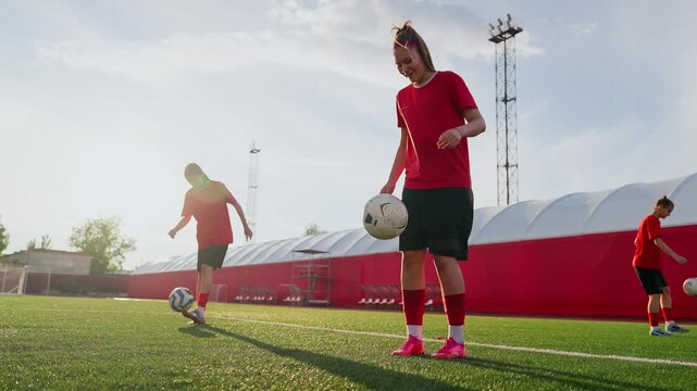Womens soccer training session on outdoor artificial turf field with focused ball control drills, coordinated teamwork, and warm sunset stadium practice atmosphere