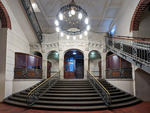 Dimly lit historic entrance hall with a grand staircase inside the Dome Cathedral in Riga, Latvia.